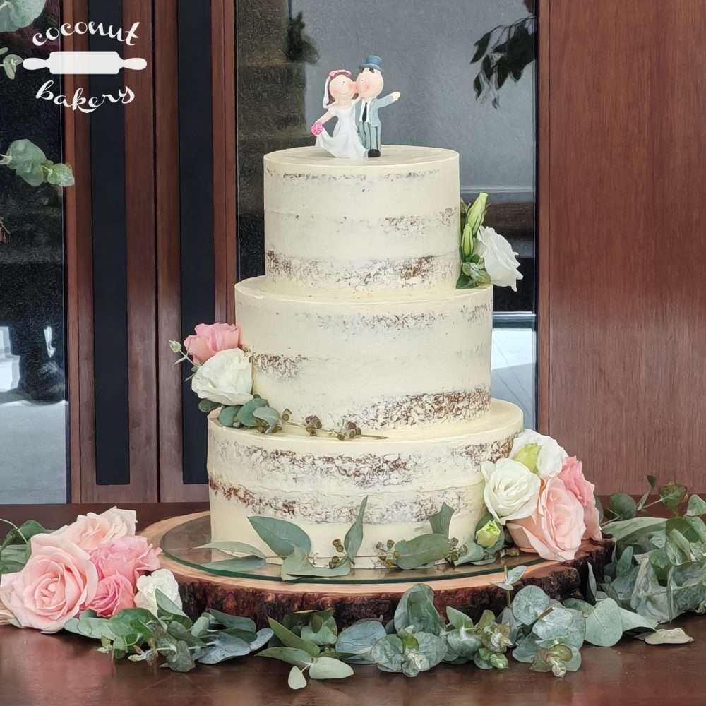 Tarta de boda decorada con flores y muñecos.
