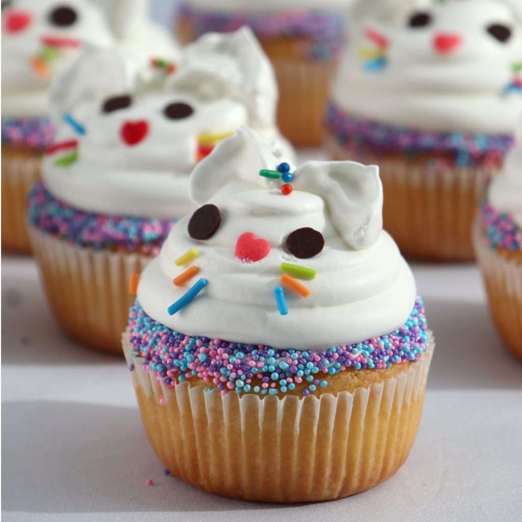 Cupcakes con decoración de cara de conejo blanca.
