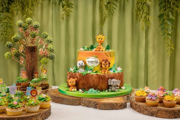 Tarta decorada con animales de la selva y cupcakes.